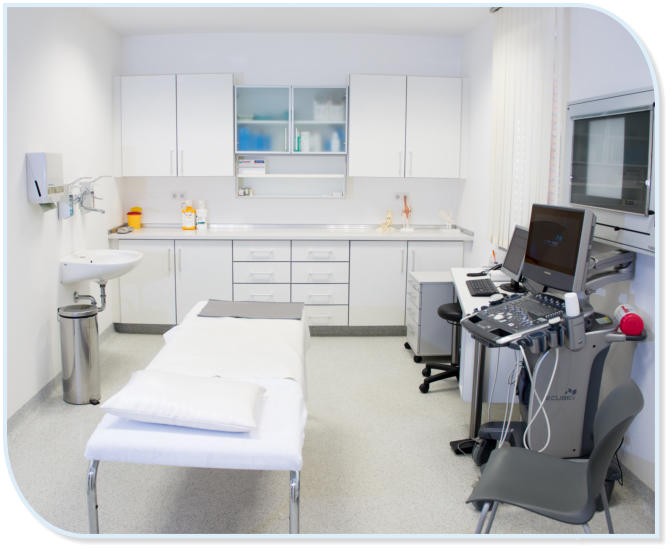 Ein moderner Behandlungsraum in einer Klinik mit einer Untersuchungsliege, Medizinschränken und einem Ultraschallgerät.