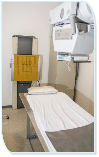 Ein Röntgengerät in einem medizinischen Raum mit einer Untersuchungsliege und einem Zielbrett.