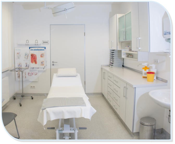 Ein sauberer Behandlungsraum in einer Arztpraxis mit einer Untersuchungsliege, Schränken und einem Diagramm der Schulter.